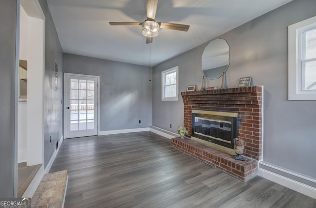 living room with ceiling fan, a fireplace, and dark wood-type flooring