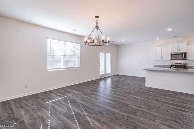 kitchen with white cabinets, stainless steel appliances, light stone counters, and a wealth of natural light