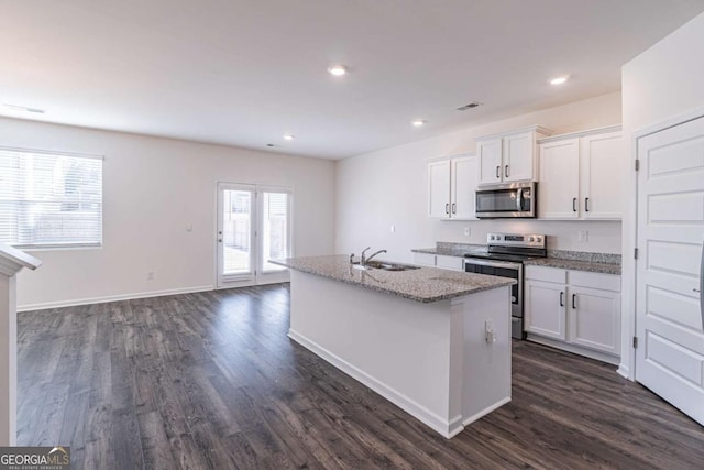 kitchen with white cabinets, appliances with stainless steel finishes, plenty of natural light, and a kitchen island with sink