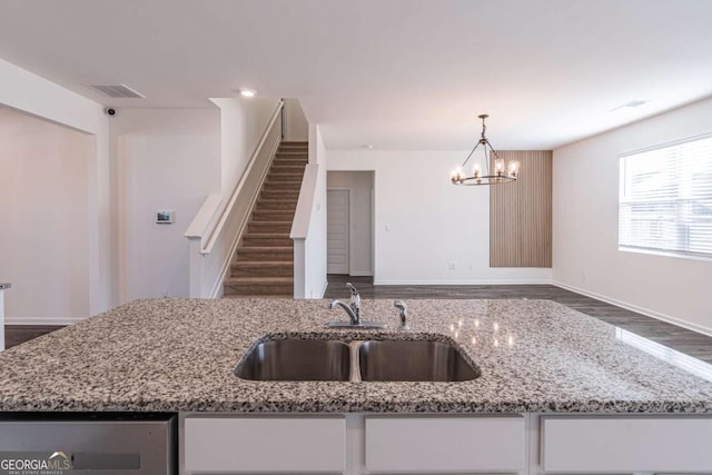 kitchen with an inviting chandelier, sink, dark hardwood / wood-style floors, decorative light fixtures, and light stone counters