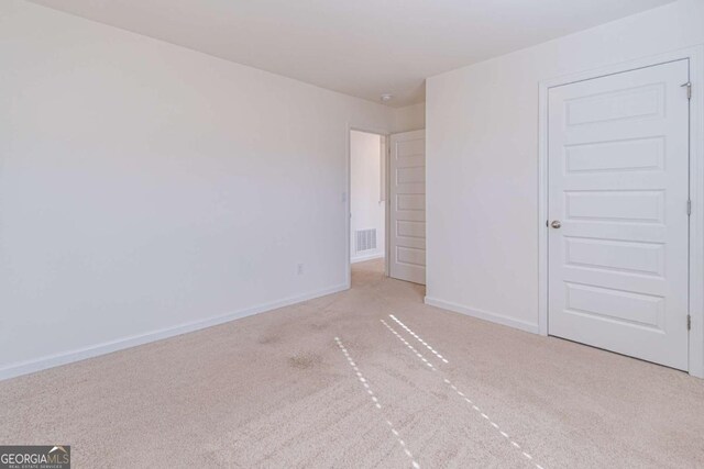 unfurnished bedroom with light colored carpet and a closet