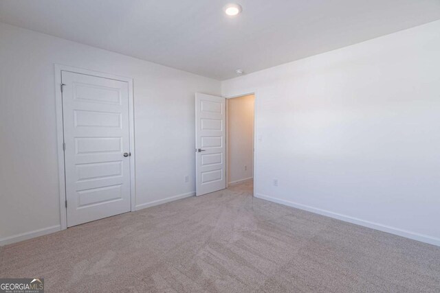 unfurnished bedroom featuring light colored carpet and a closet