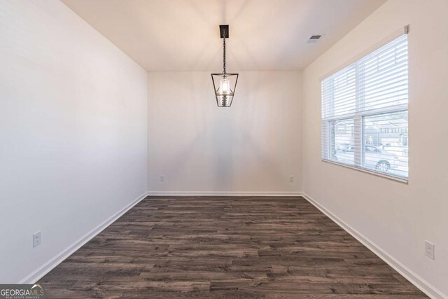 unfurnished dining area featuring dark hardwood / wood-style flooring and an inviting chandelier