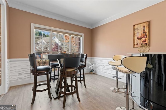 dining space with ornamental molding and light hardwood / wood-style flooring