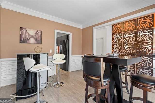 bar featuring stainless steel fridge, crown molding, and wood-type flooring