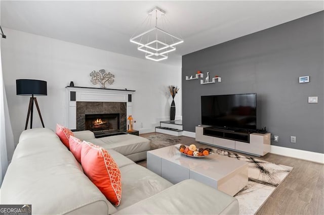 living room with a premium fireplace, wood-type flooring, and an inviting chandelier