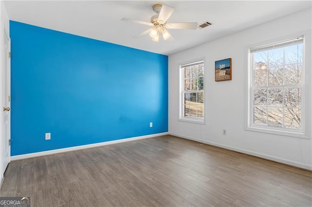 spare room with wood-type flooring, plenty of natural light, and ceiling fan