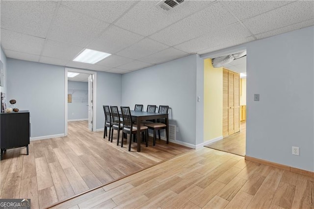 dining space featuring electric panel, light hardwood / wood-style flooring, and a drop ceiling