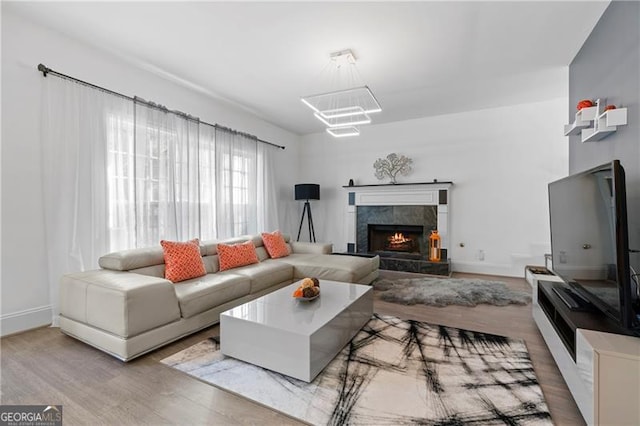 living room with a tile fireplace, wood-type flooring, and an inviting chandelier