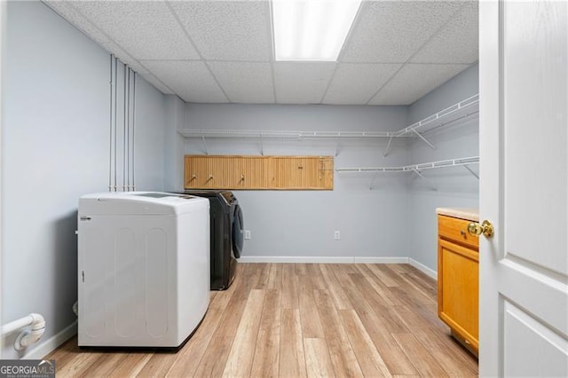 laundry area featuring washing machine and clothes dryer and light wood-type flooring