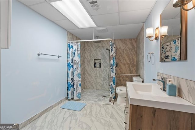 bathroom with a shower with curtain, toilet, a paneled ceiling, vanity, and tile walls