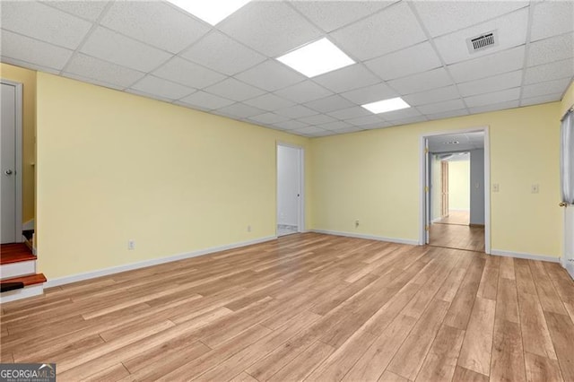 empty room featuring a drop ceiling and light hardwood / wood-style flooring