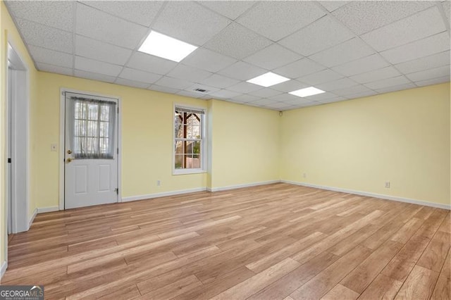 empty room featuring a drop ceiling and light wood-type flooring