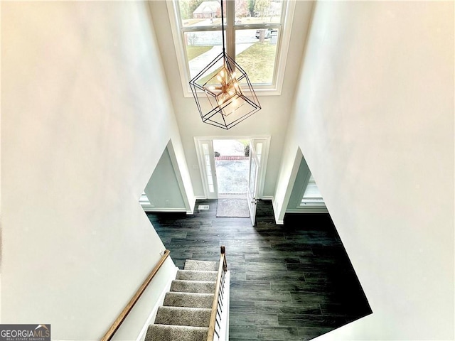 foyer entrance featuring a towering ceiling and dark wood-type flooring