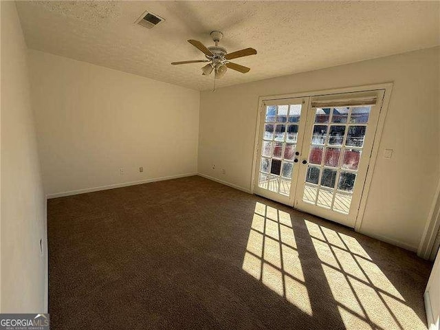 empty room featuring dark colored carpet, a textured ceiling, and french doors