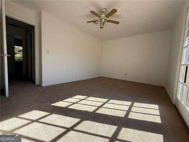 carpeted empty room featuring ceiling fan and a textured ceiling