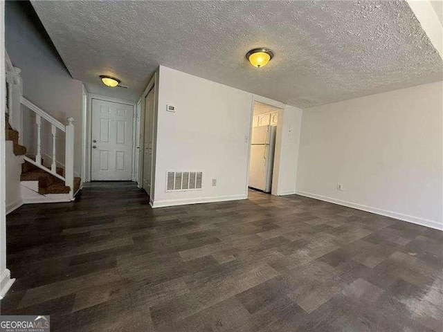 unfurnished room featuring dark wood-type flooring and a textured ceiling