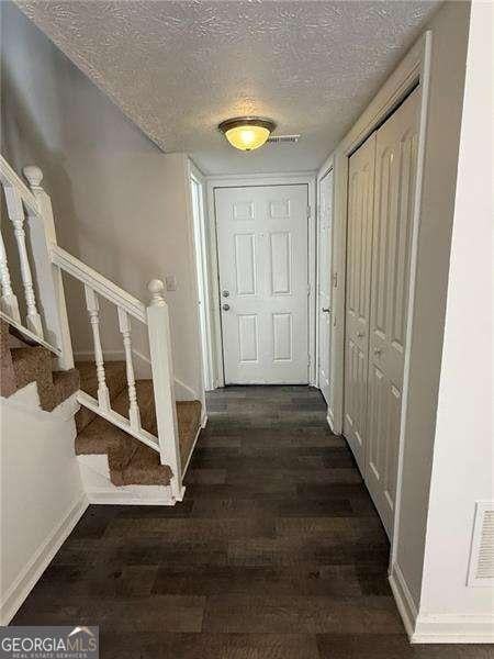 hallway featuring dark hardwood / wood-style flooring and a textured ceiling