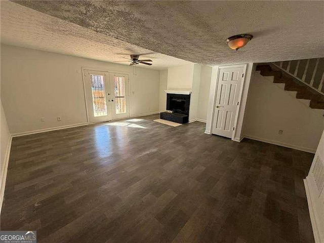 unfurnished living room featuring ceiling fan, french doors, dark wood-type flooring, and a textured ceiling