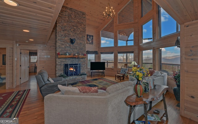 living room featuring hardwood / wood-style floors, a stone fireplace, wood ceiling, and a wealth of natural light