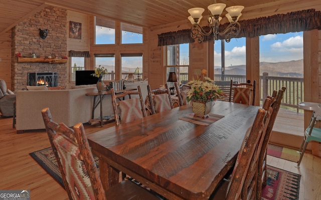 dining space featuring a fireplace, light hardwood / wood-style flooring, lofted ceiling, and a notable chandelier