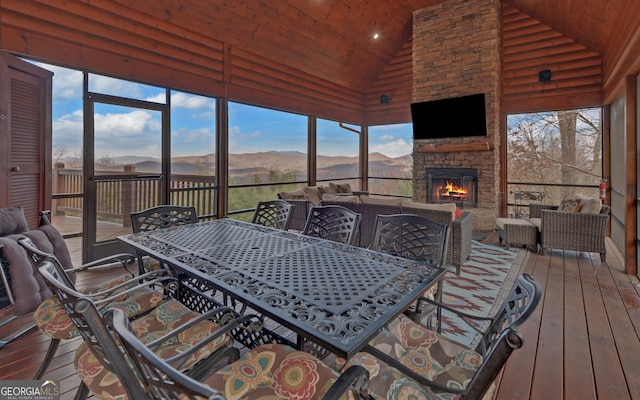 sunroom with an outdoor stone fireplace, a healthy amount of sunlight, wooden ceiling, and vaulted ceiling