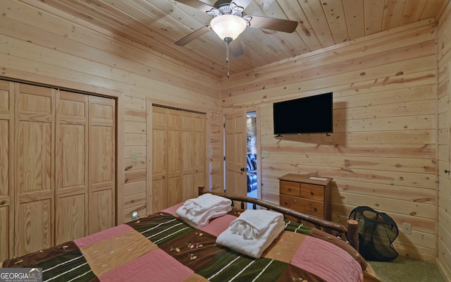 carpeted bedroom with ceiling fan, multiple closets, and wood walls