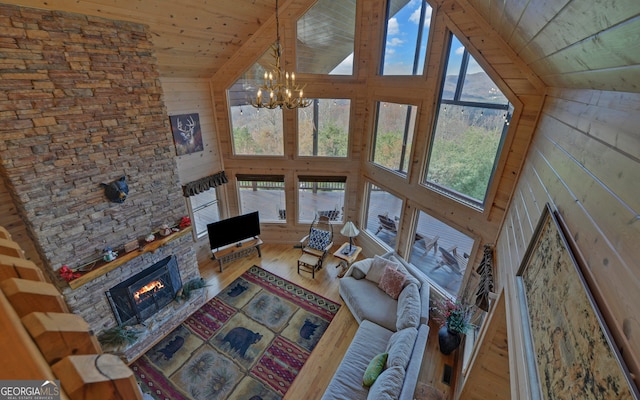 unfurnished living room with wood ceiling, high vaulted ceiling, a chandelier, hardwood / wood-style floors, and a stone fireplace