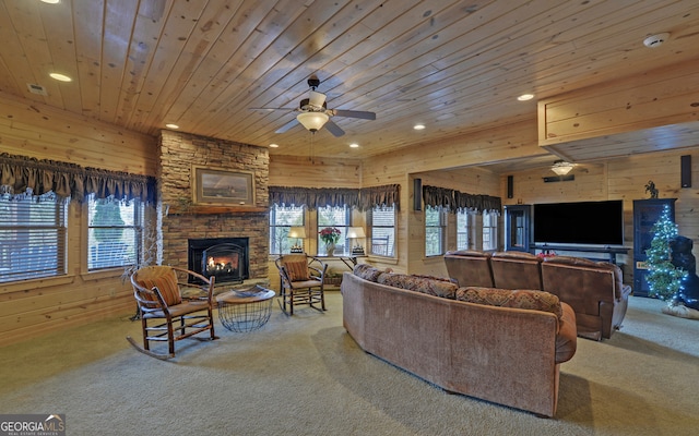 living room featuring wooden ceiling, a stone fireplace, wooden walls, ceiling fan, and carpet floors