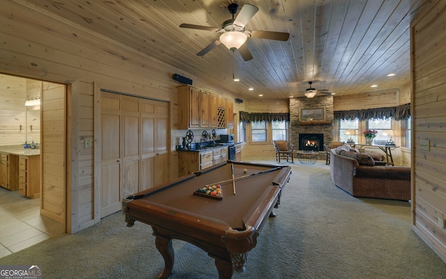 game room featuring wooden walls, a stone fireplace, light colored carpet, and pool table