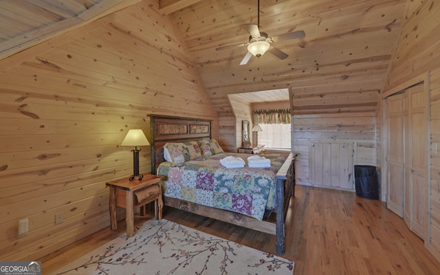 bedroom with wooden walls, hardwood / wood-style floors, ceiling fan, and vaulted ceiling