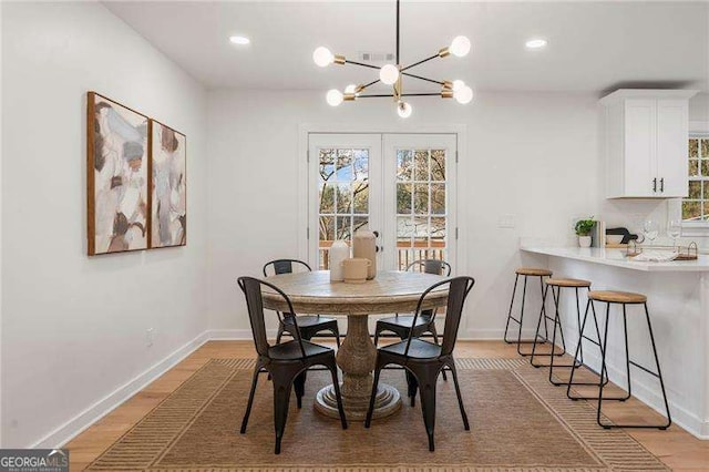 dining area featuring french doors, light hardwood / wood-style flooring, and a chandelier