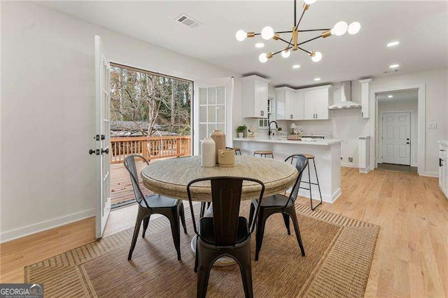 dining area featuring sink, a notable chandelier, and light wood-type flooring