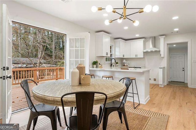 dining room featuring sink, a notable chandelier, and light wood-type flooring