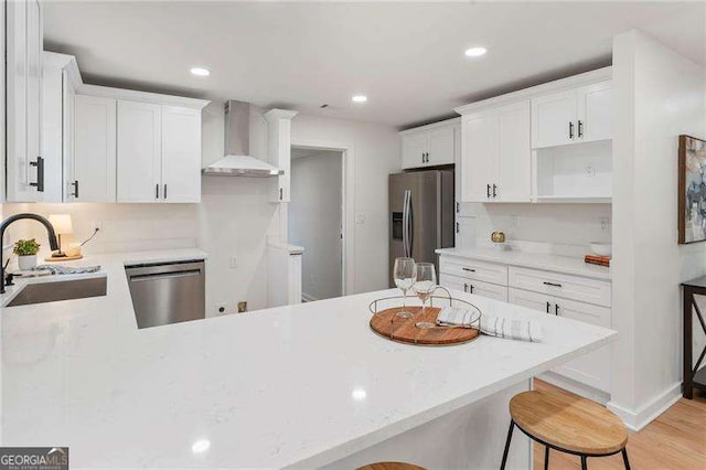 kitchen featuring white cabinetry, sink, wall chimney exhaust hood, and appliances with stainless steel finishes