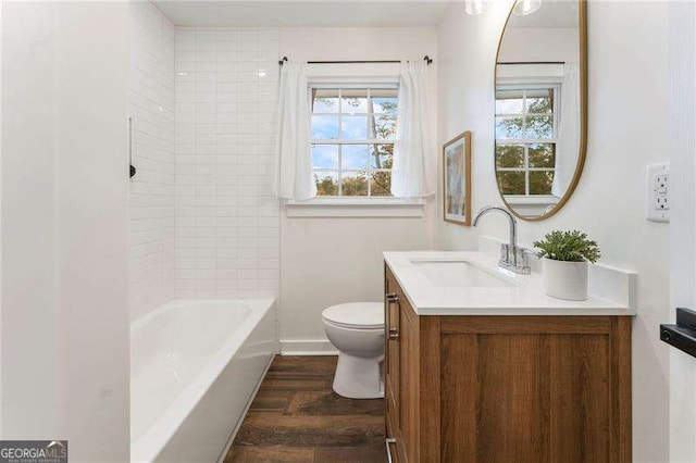 full bathroom with hardwood / wood-style floors, vanity, toilet, and tiled shower / bath