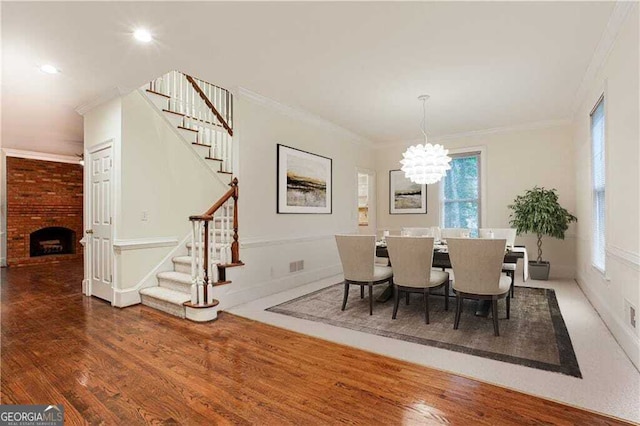 dining space featuring a fireplace, a chandelier, dark hardwood / wood-style floors, and ornamental molding