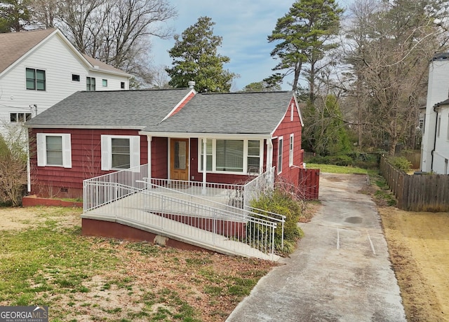 view of front of house with a porch, crawl space, a shingled roof, and fence