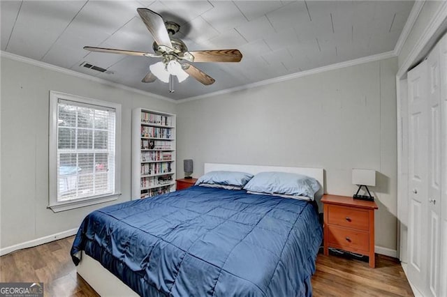 bedroom featuring ceiling fan, crown molding, and dark wood-type flooring