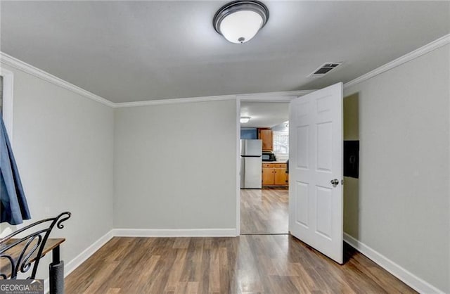 unfurnished room featuring hardwood / wood-style floors and crown molding