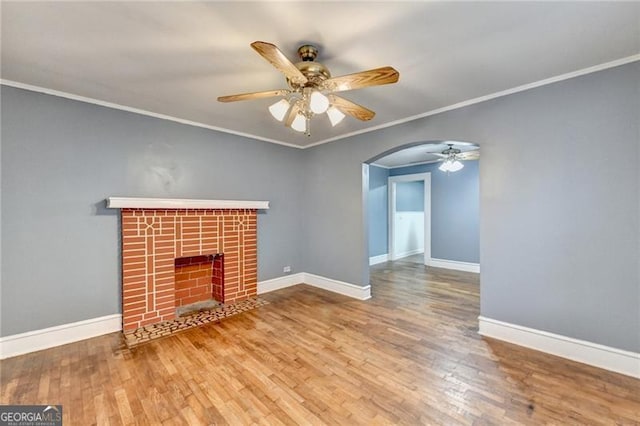 unfurnished living room featuring hardwood / wood-style flooring, ceiling fan, ornamental molding, and a brick fireplace