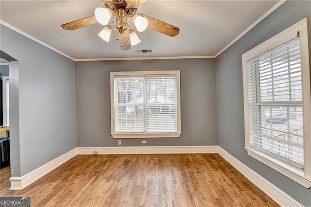 empty room featuring plenty of natural light, light hardwood / wood-style floors, and ornamental molding