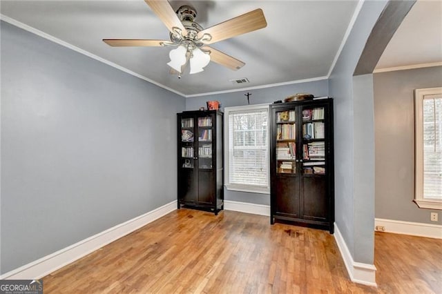 interior space with light hardwood / wood-style floors, a wealth of natural light, crown molding, and ceiling fan