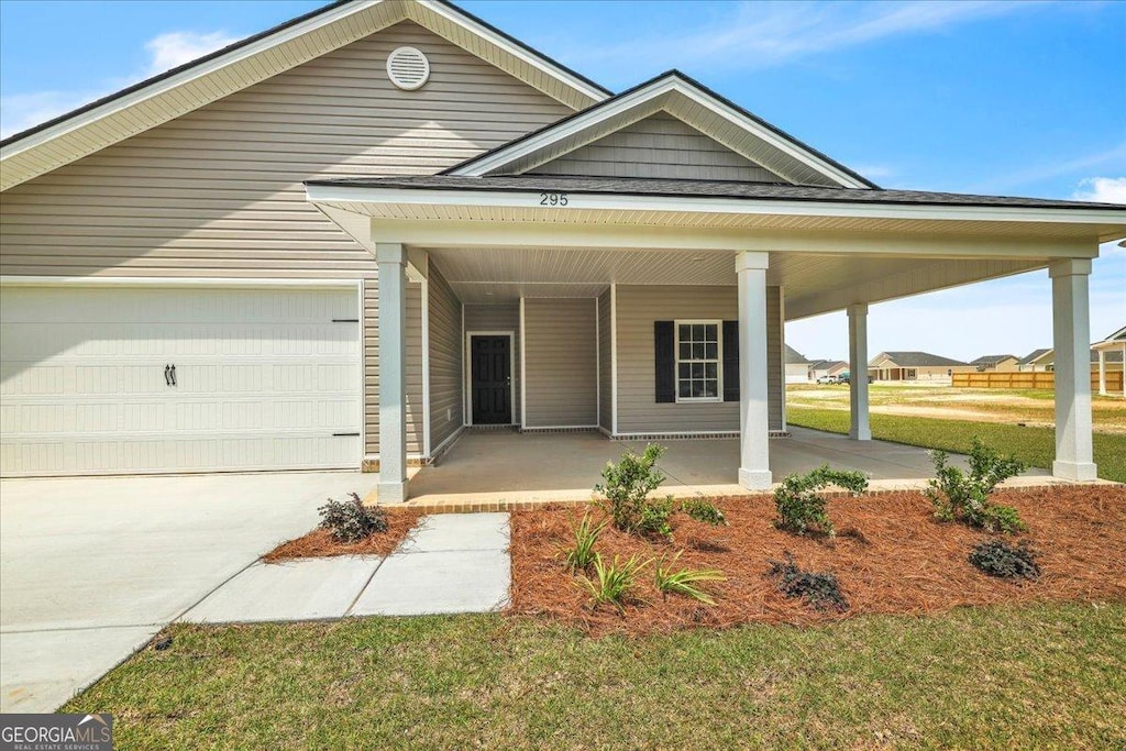 295 Lanier Rd NE, Ludowici, GA 31316 - view of front of property with covered porch, an attached garage, concrete driveway, and a front yard