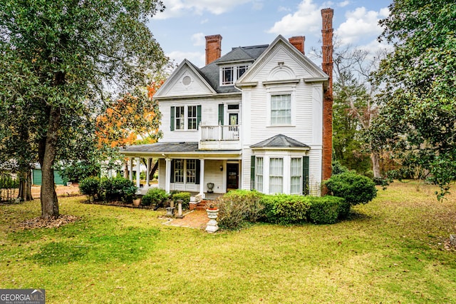 view of front facade featuring a porch, a balcony, and a front lawn