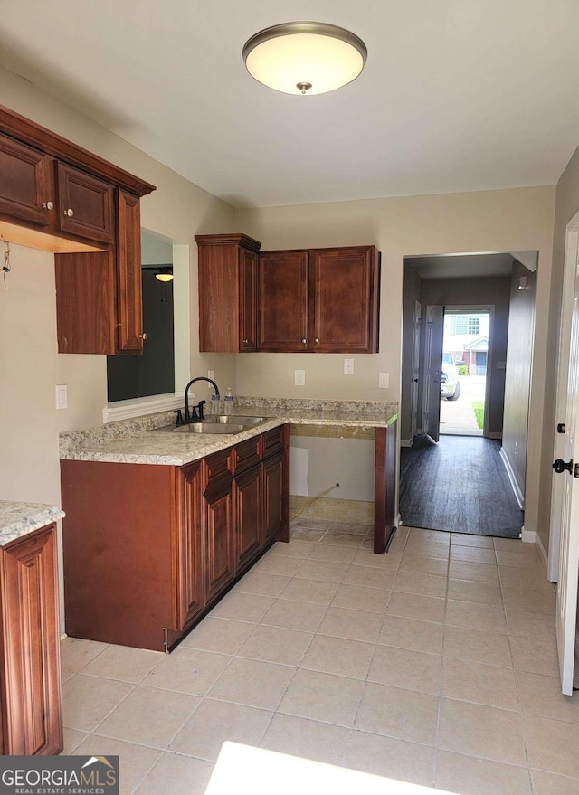 kitchen featuring light wood-type flooring, light stone counters, and sink