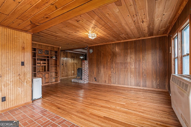 unfurnished living room featuring a wood stove, wood walls, light hardwood / wood-style flooring, and wood ceiling