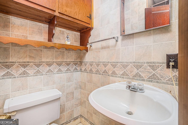 bathroom with sink, tile walls, and toilet