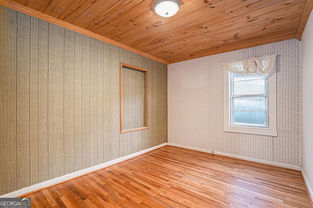 spare room featuring light wood-type flooring, crown molding, and wood ceiling