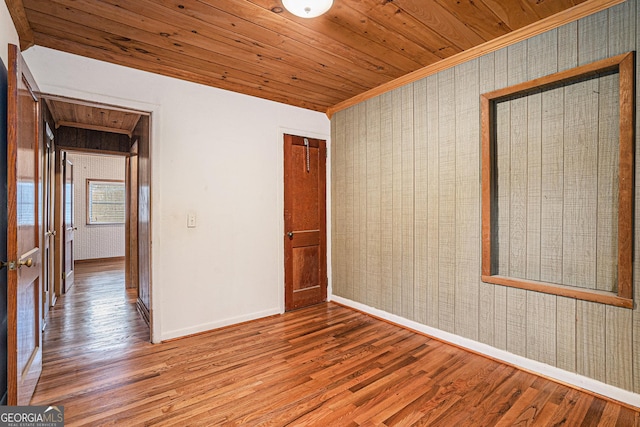 spare room featuring hardwood / wood-style floors, crown molding, wood walls, and wood ceiling